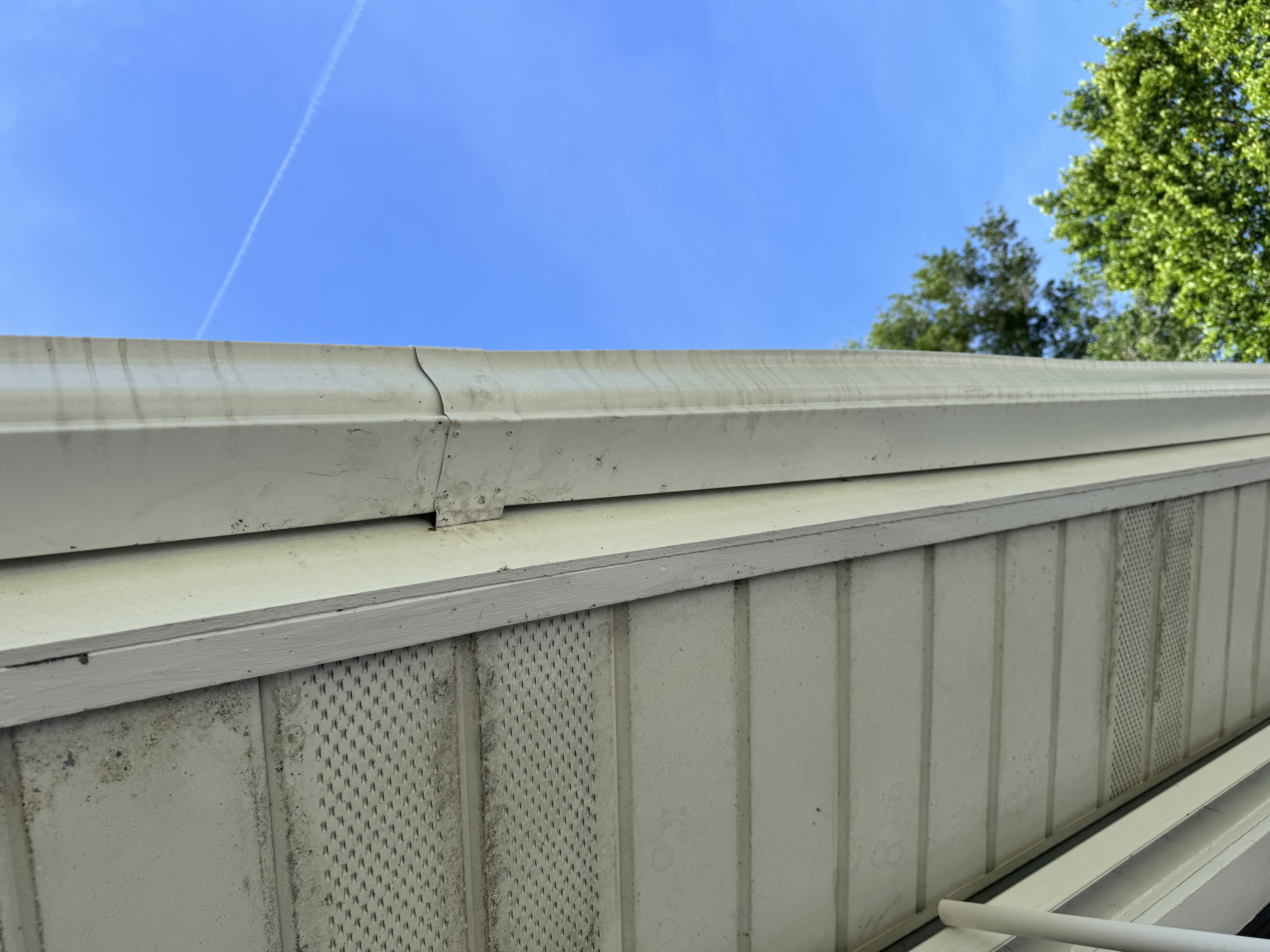 Repaired gutter joint and soffit section on a residential roofline