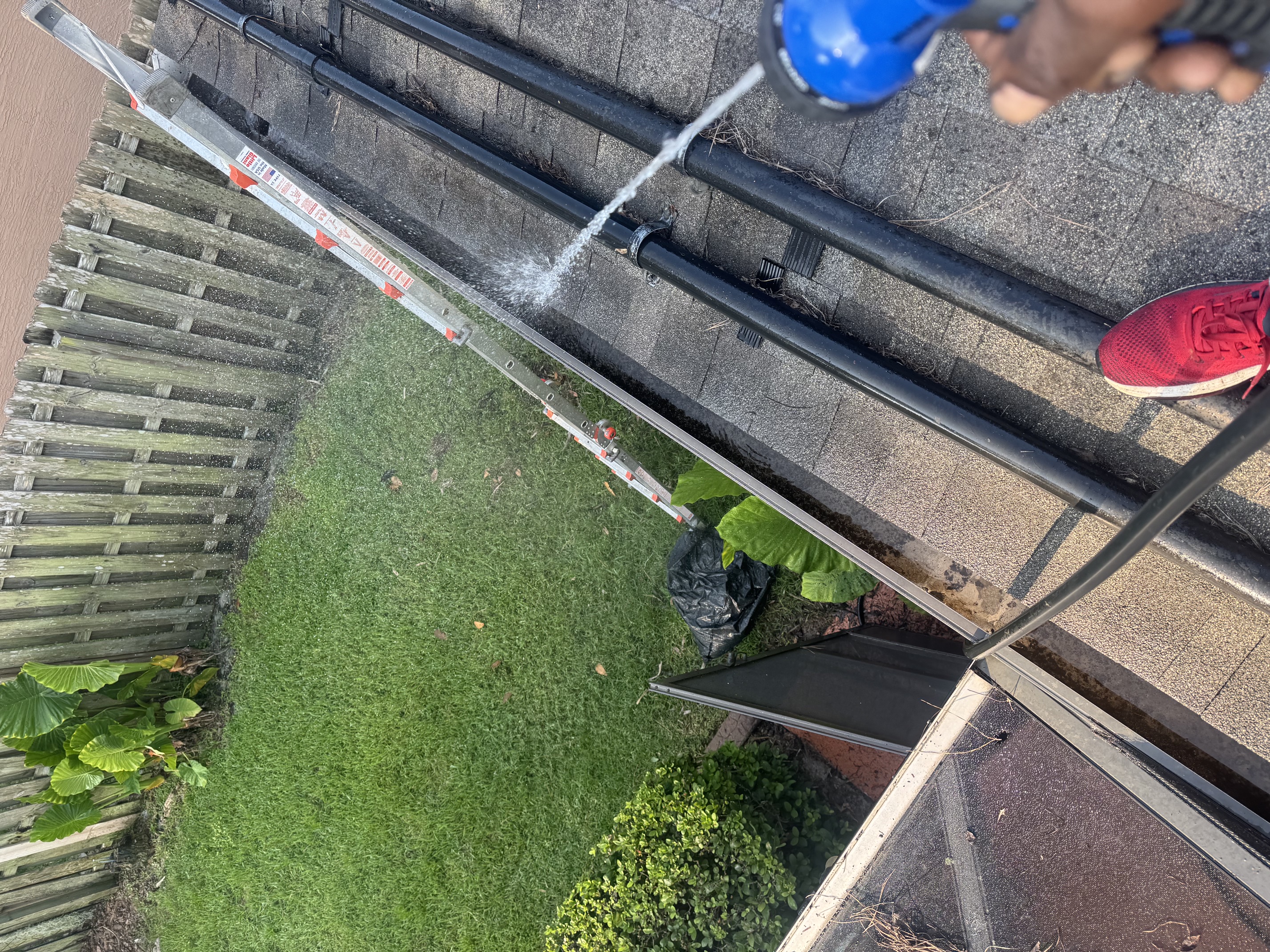 Flushing a rear gutter run clear during a cleaning job